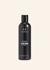 Black shower gel bottle with 'The Body Shop' branding on a beige background