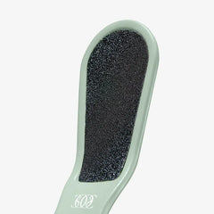 Green foot scrubber with black sandpaper surface on a white background