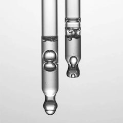 Two glass droppers with liquid on a light gray background