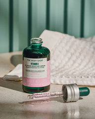 The Body Shop Vitamin E serum bottle with dropper on a neutral background