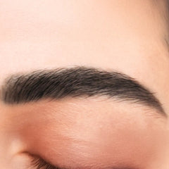 Close-up of a person's eyebrow on a neutral background