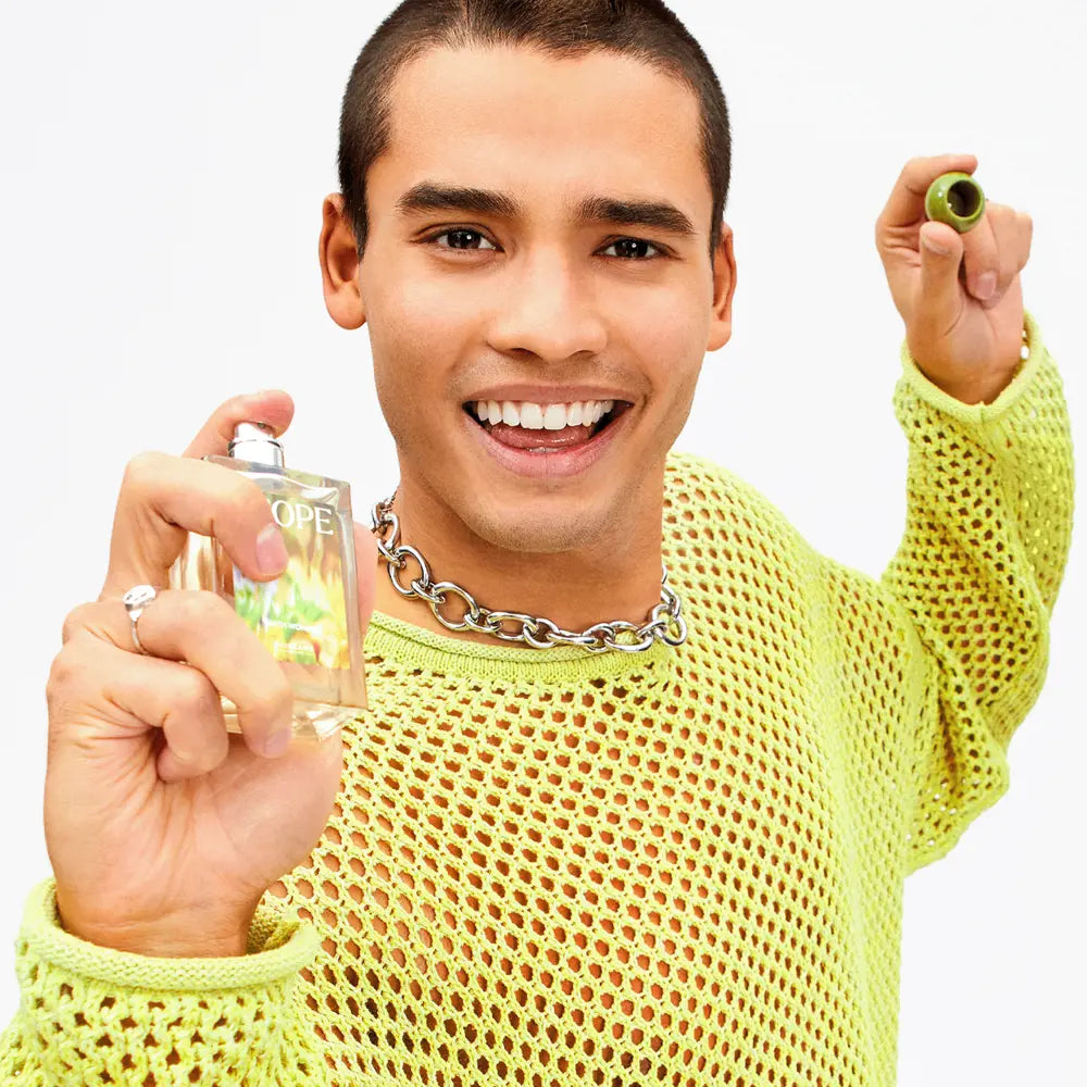 Man in a yellow sweater holding a glass with a green olive and a shot glass with a drink.