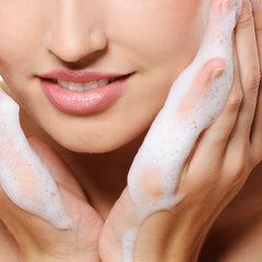Close-up of a woman's face with soapy hands