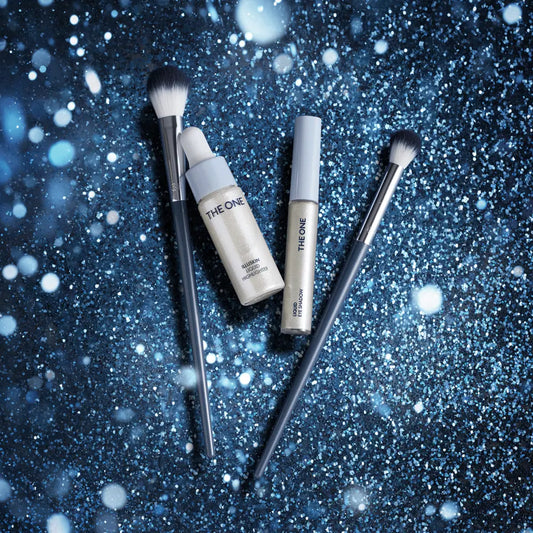Makeup brushes and bottles on a glittery blue background