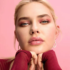 Woman with pink makeup and red top against a pink background
