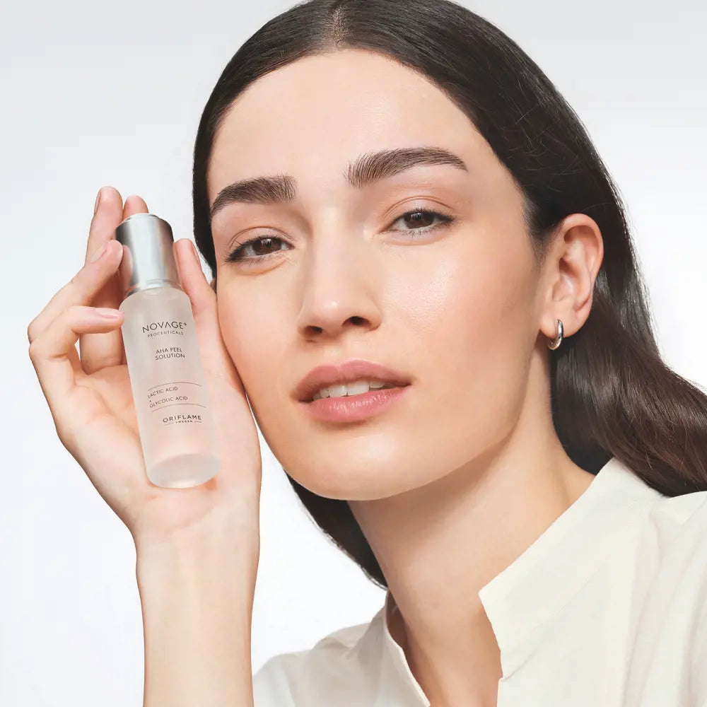 Woman holding a skincare bottle with a plain background