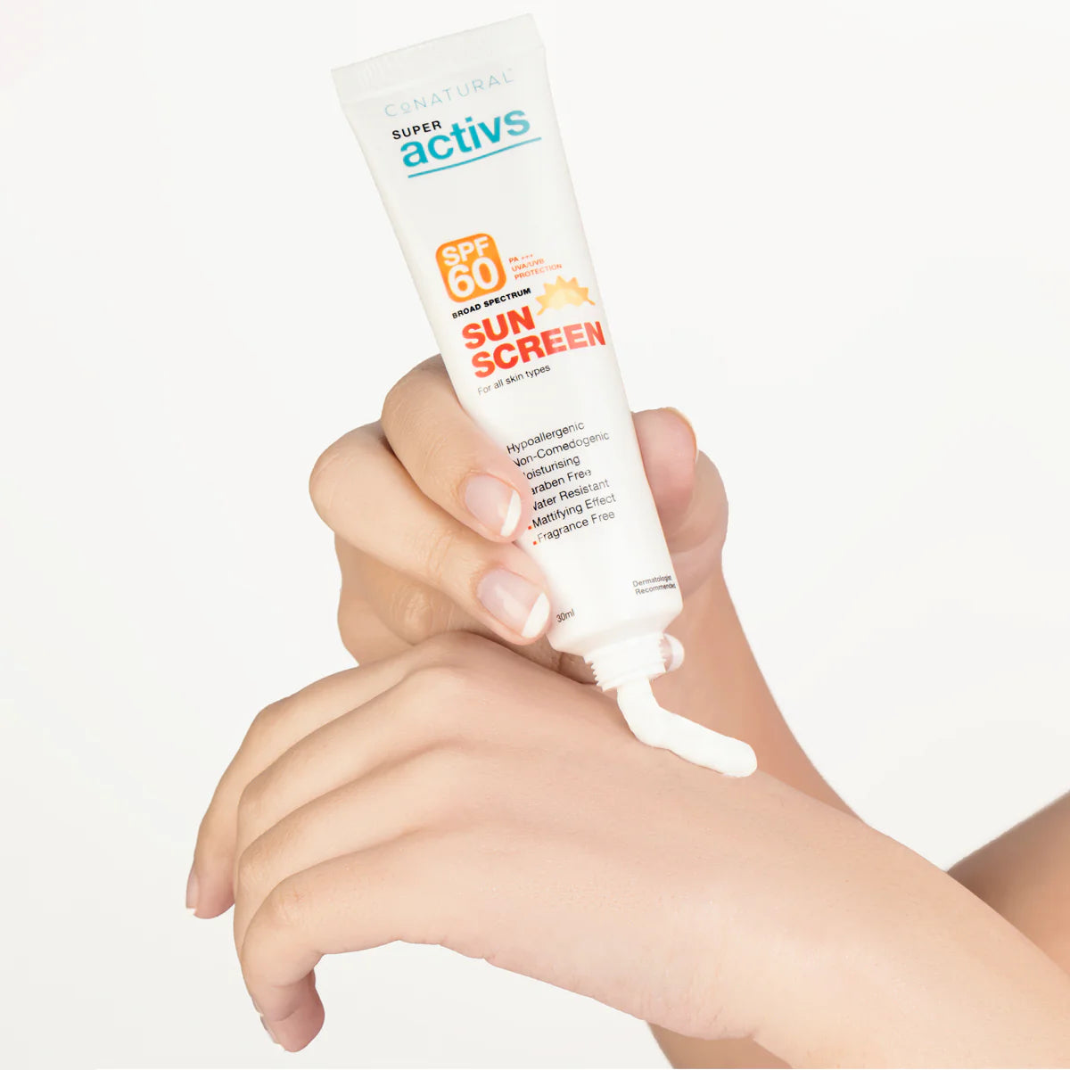 Hand applying sunscreen cream from a tube labeled 'Super Activs' on a white background