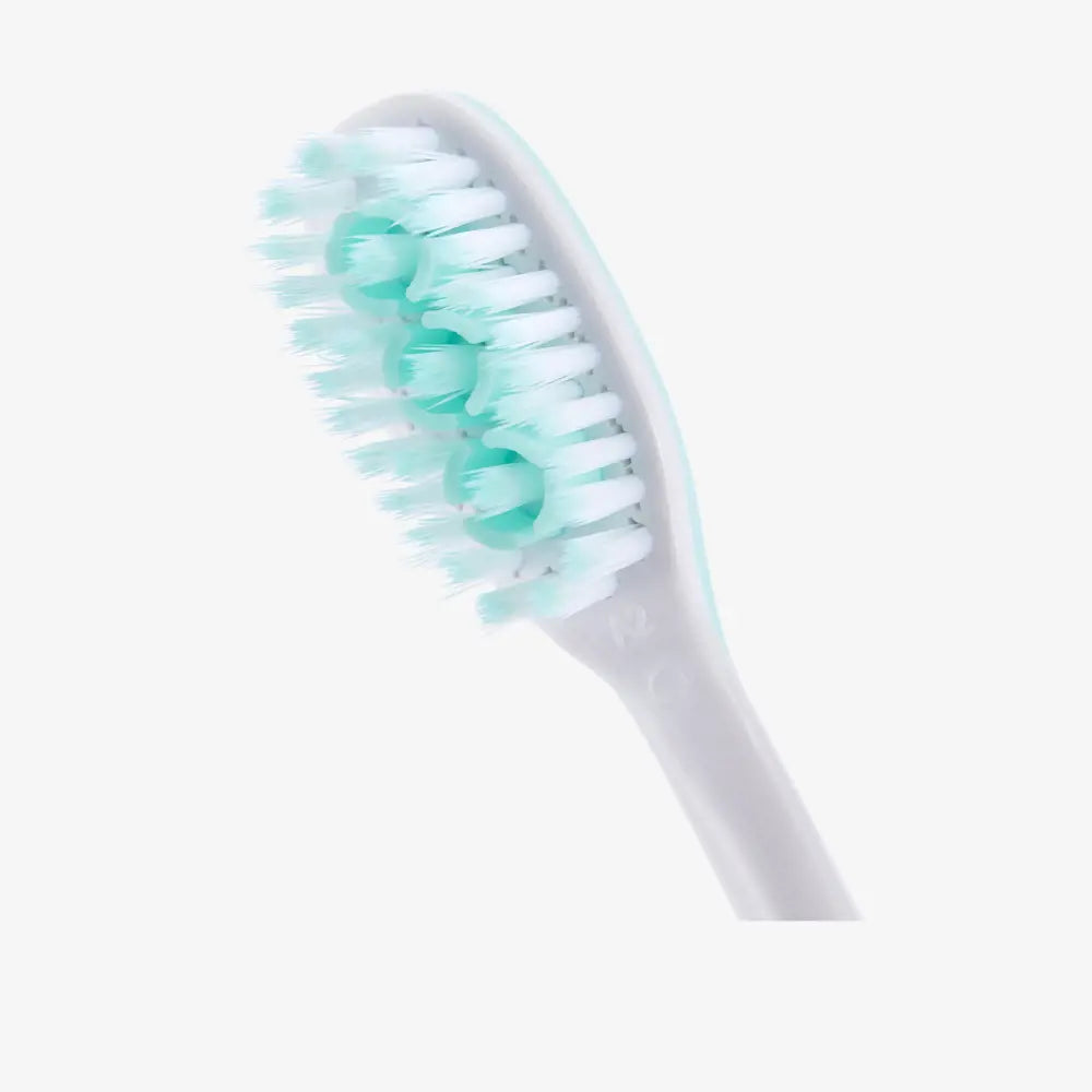 White toothbrush with green bristles on a white background
