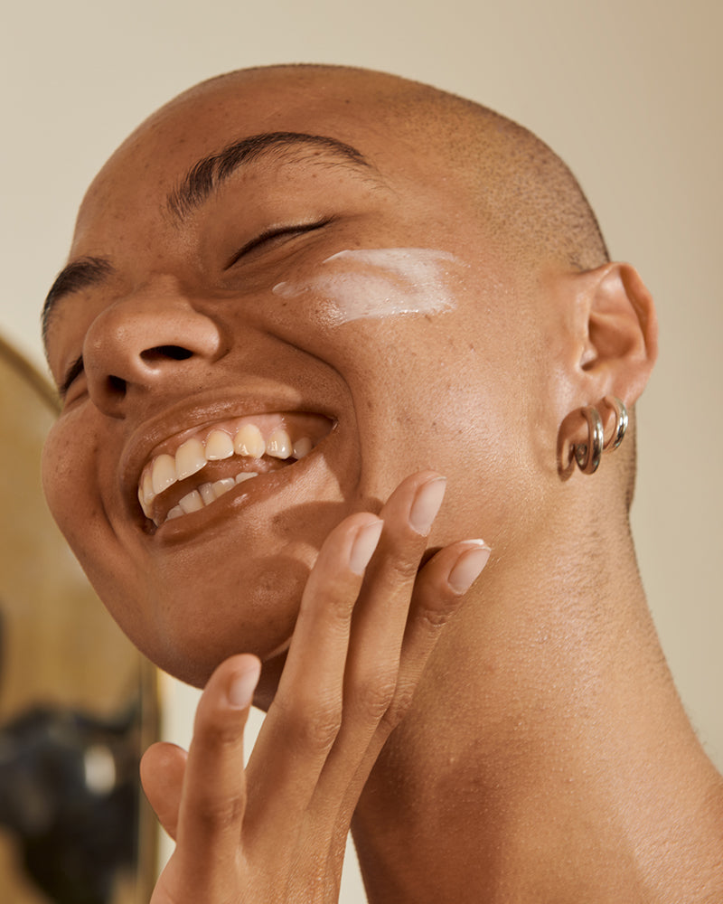 Person applying cream to their face with a blurred background